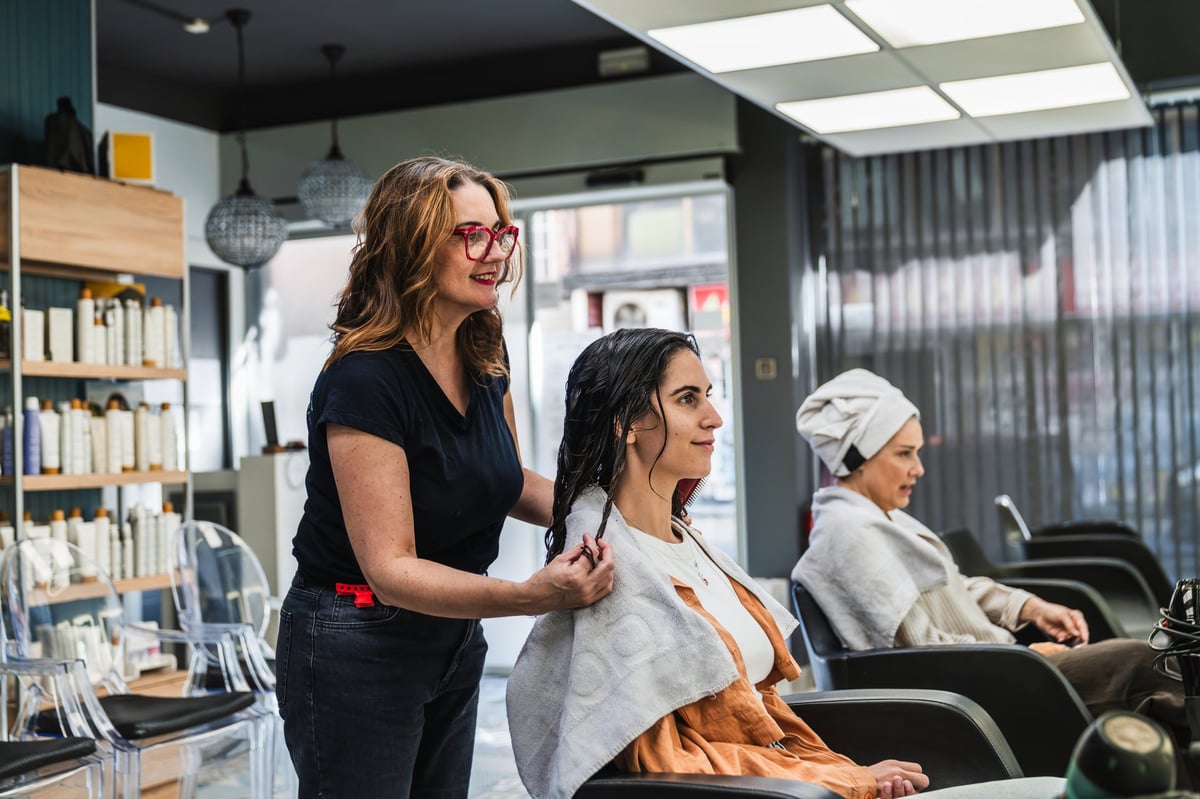 Hairdresser preparing client's hair in modern salon